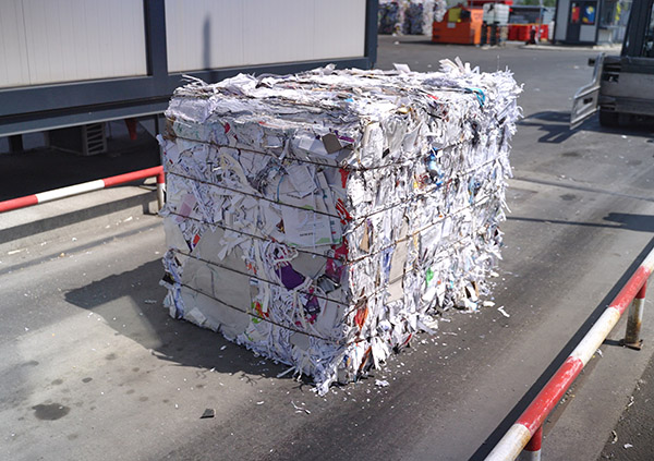Stisnjena bala odpadnega papirja, pripravljena za recikliranje v zbirnem centru.