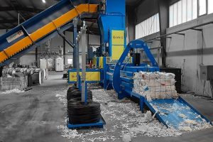 ANIS Kanalballenpresse in einer Industrieanlage, die gepresste Papierballen auswirft und über ein Förderband mit Material beschickt wird.