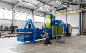 Maintenance of ANIS automatic baler wire tying system on a channel baler inside an industrial workshop.