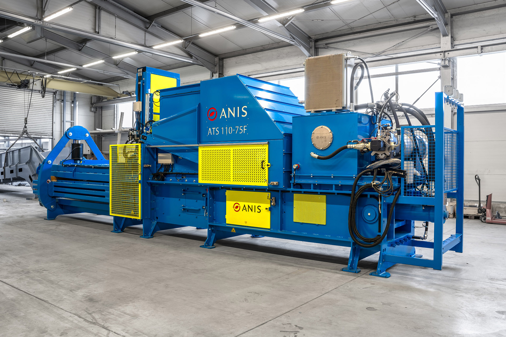 Blue ANIS ATS 110-75F industrial press in a factory with yellow protective guards highlighting essential Baler safety features.