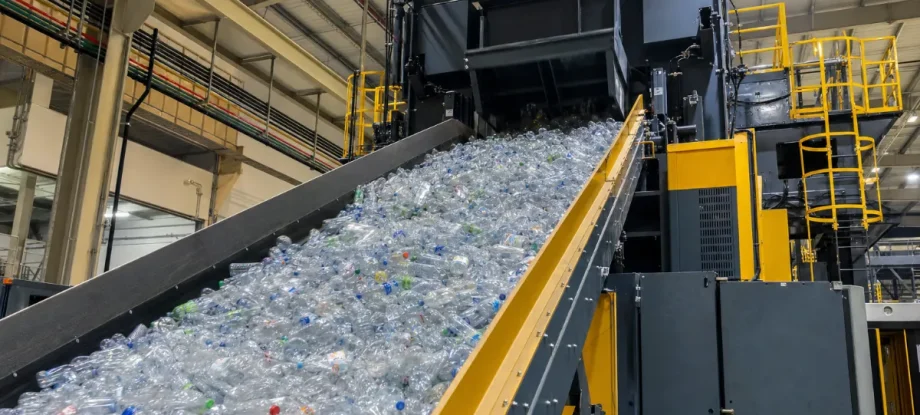 Für das PET Flaschen Recycling transportiert ein riesiges Förderband unzählige lose PET-Flaschen in den Trichter einer modernen Kanalballenpresse.