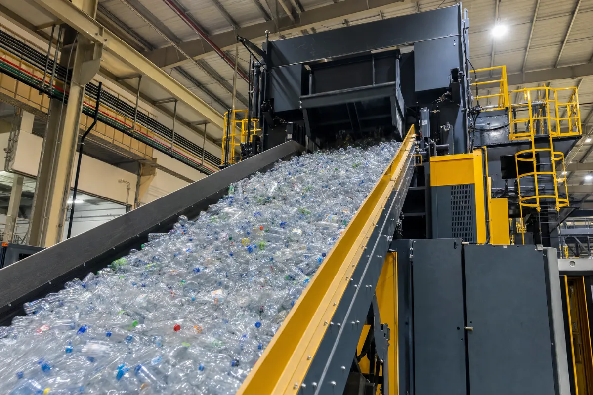 Für das PET Flaschen Recycling transportiert ein riesiges Förderband unzählige lose PET-Flaschen in den Trichter einer modernen Kanalballenpresse.